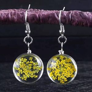 Glass ball earrings with real dried yellow flowers inside.